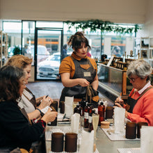 Load image into Gallery viewer, People tasting drinks at a bar with a focus on a woman in an apron.